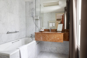 salle de bain en marbre avec baignoire et lavabo Hôtel de Seine paris