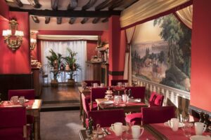 salle petit-déjeuner avec fresque, tissus rouge, tables dressées hotel des 2 continents paris saint germain des prés